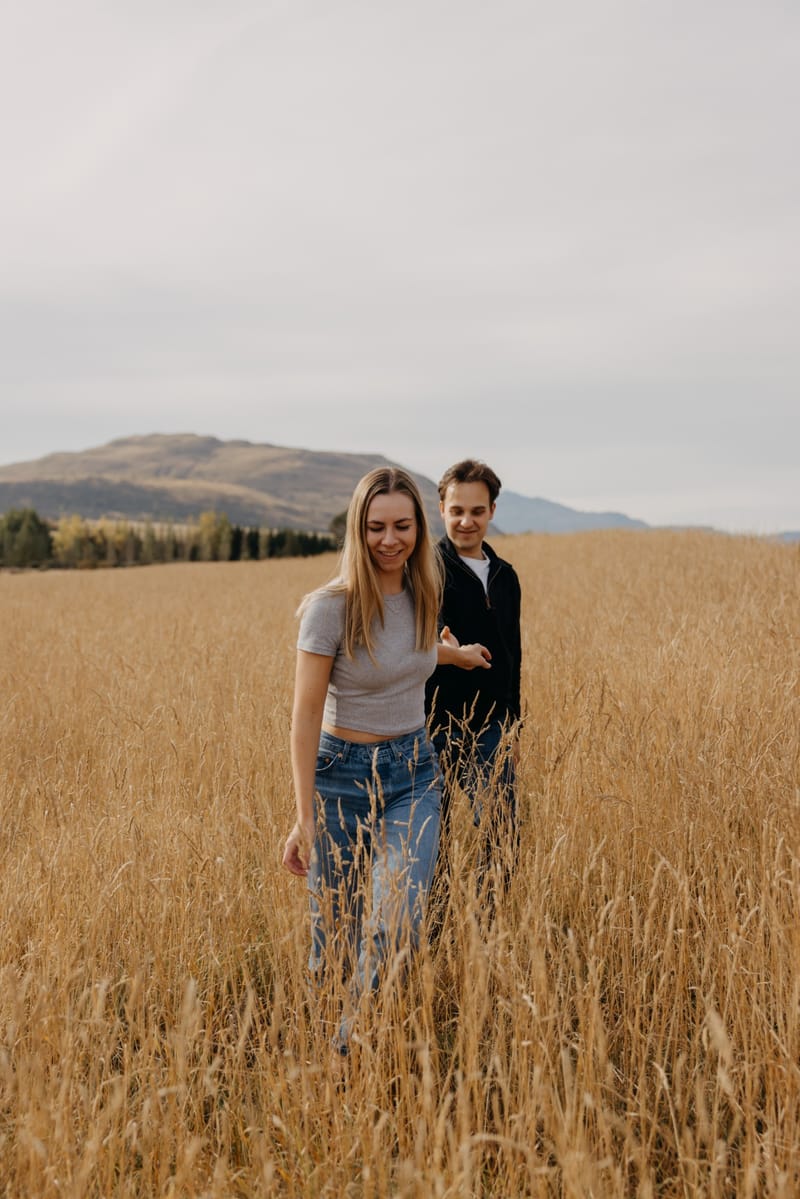 Matia and Jillian laughing as they walk through tall golden grass